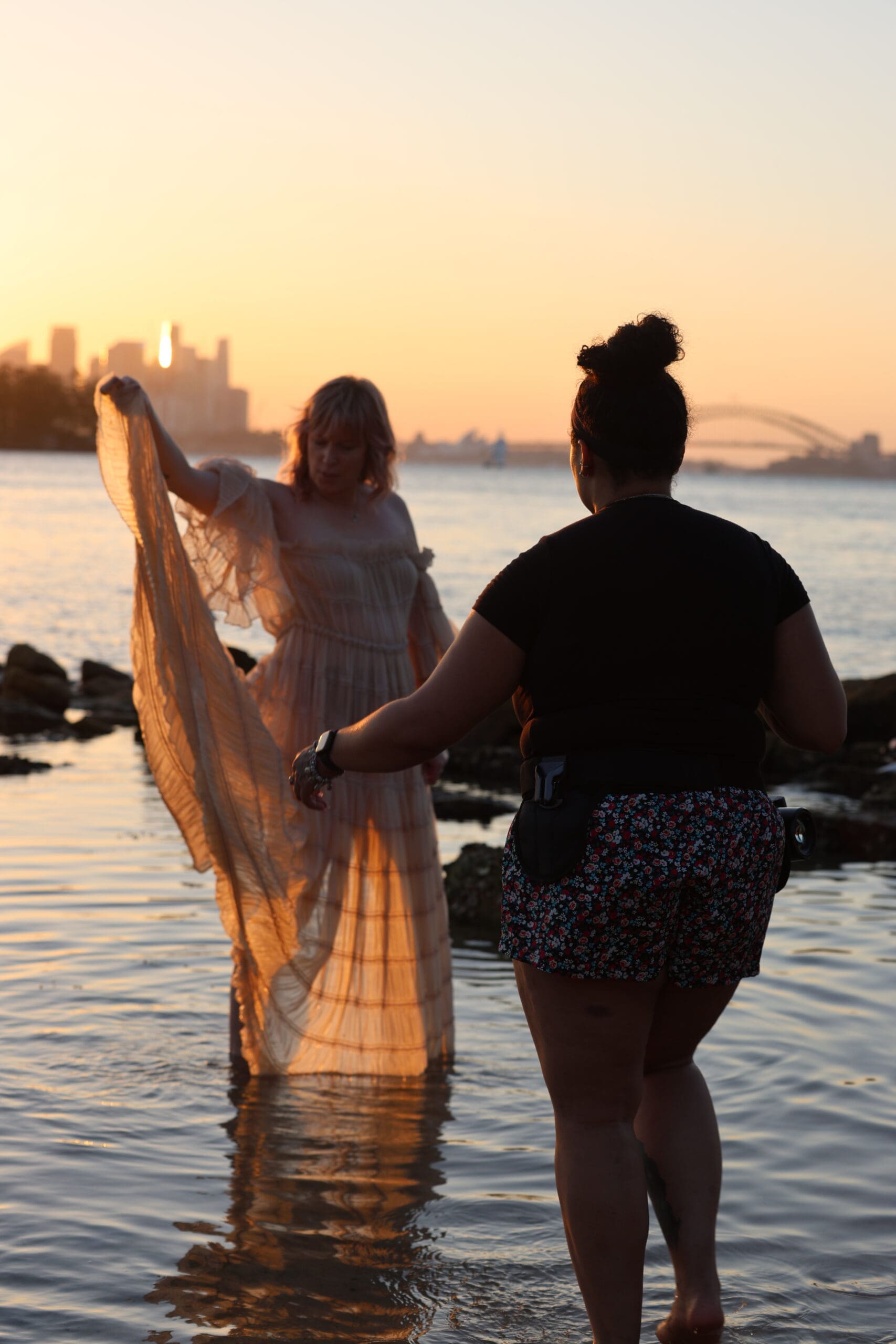 Mary Edelkind working at Milk Beach in Sydney, NSW wearing a Spider Holster belt system, capturing candid moments during a coastal photoshoot with ocean views and natural light.